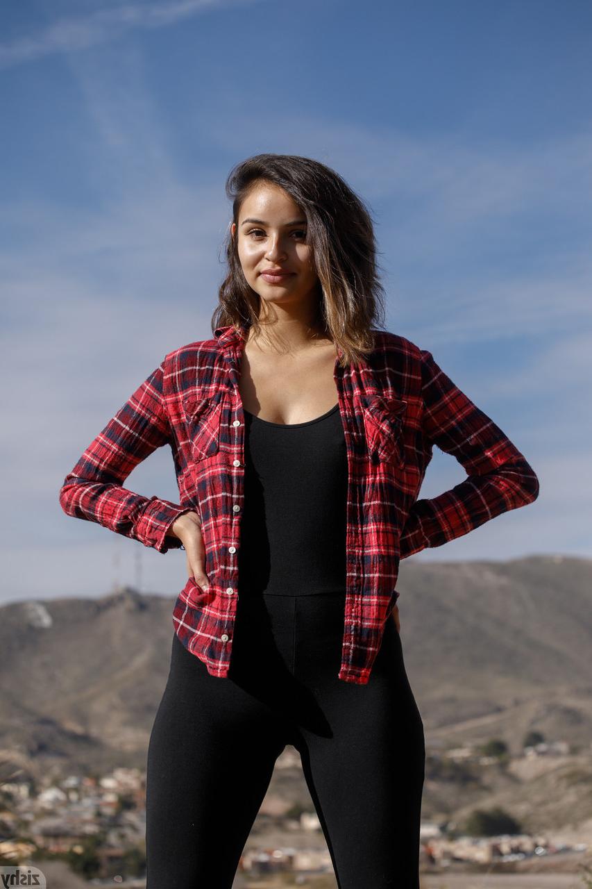 12P La pequeña latina Alejandra Cobos posa con pantalones ajustados y camisa en público
