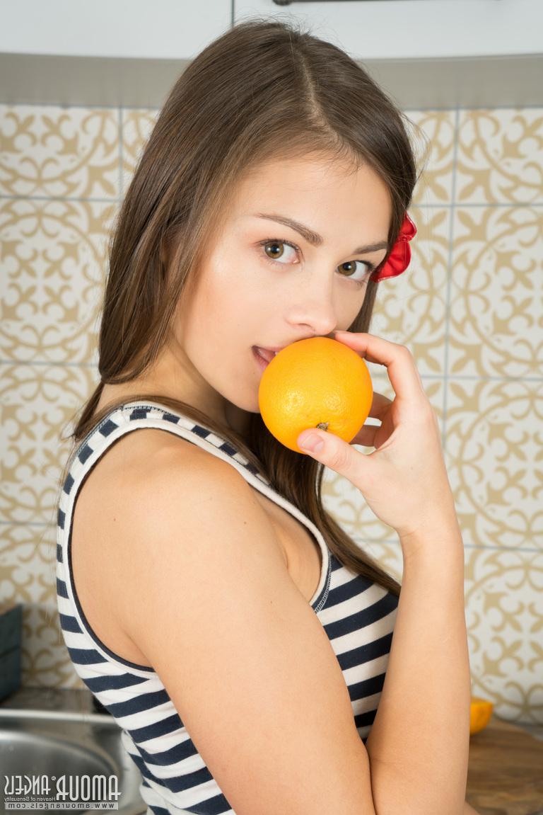 20P La jolie jeune Sabrina coupe une orange avant de poser dans la cuisine totalement nue.