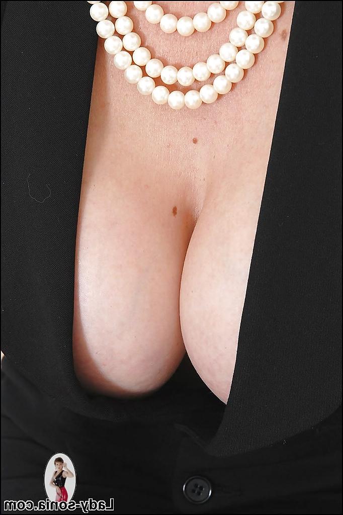 15P Wohlgeformte reife Dame mit Brille posiert in einem Kleid mit tiefem Ausschnitt