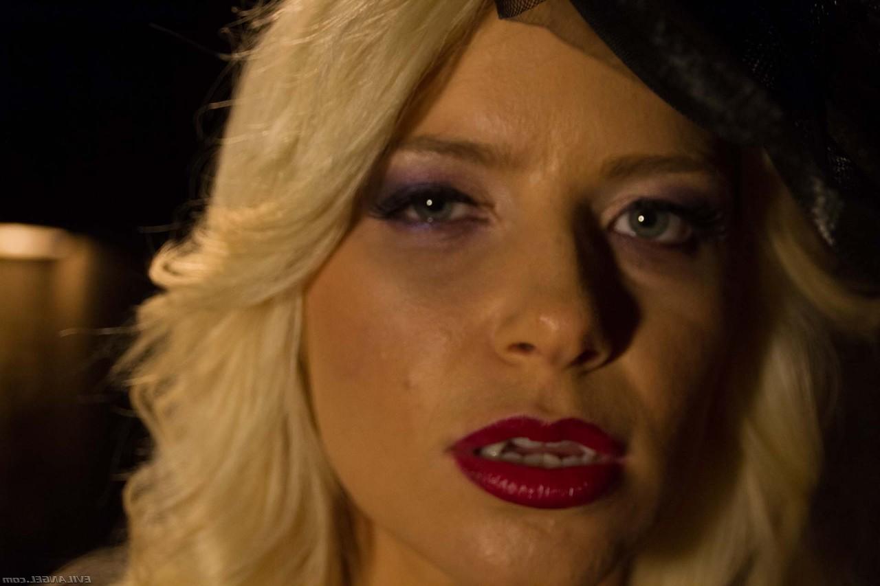 17P Blonde vampire exposes her fangs and boobs in a poorly lit cellar