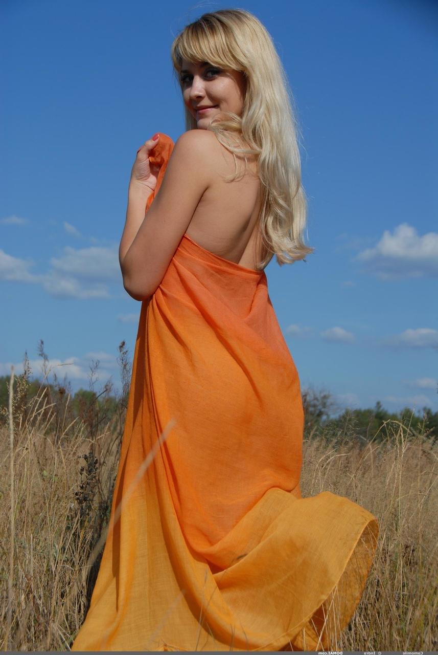 17P Jeune fille blonde à la recherche tient un tournesol tout en posant nue dans un champ de campagne