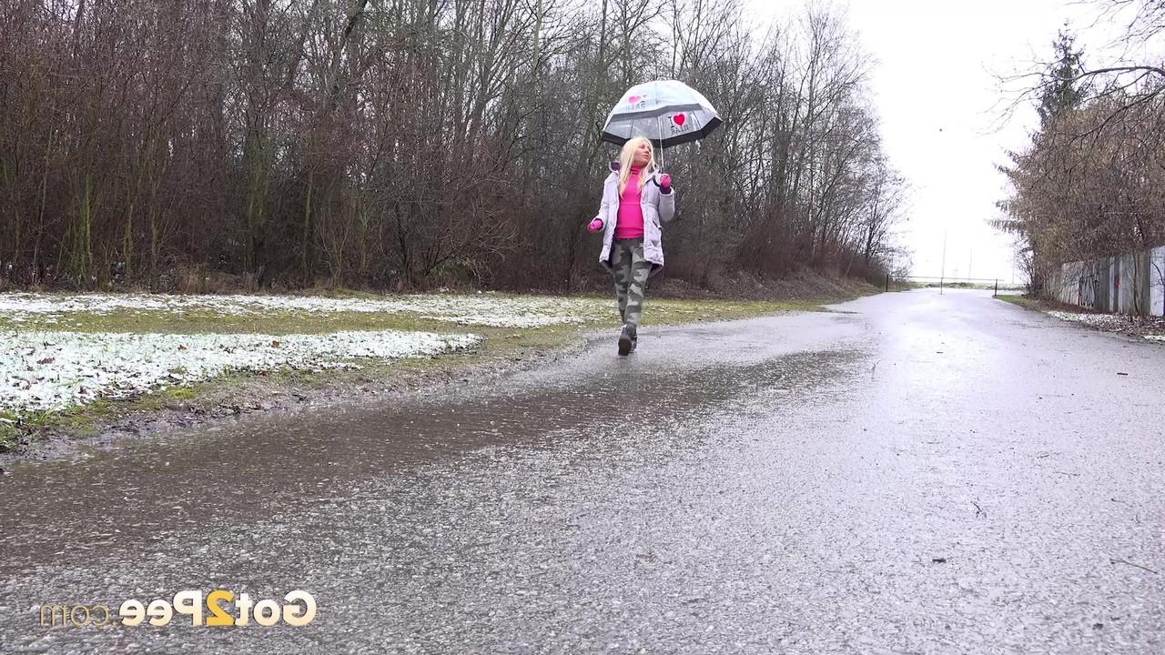 15P A loira Caroli mija em uma estrada pavimentada durante uma chuva