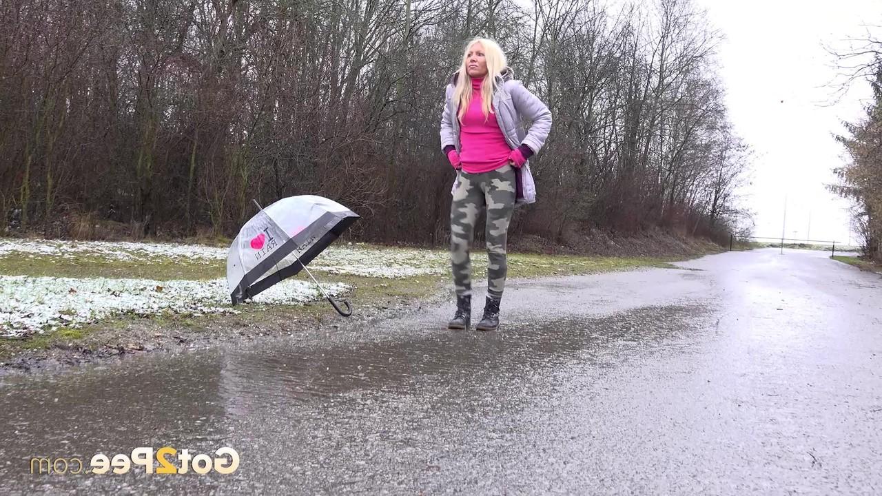 15P A loira Caroli mija em uma estrada pavimentada durante uma chuva