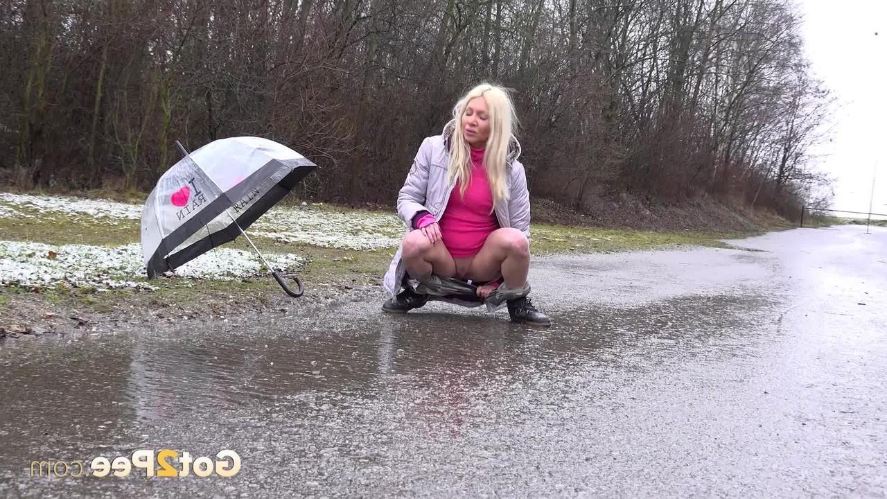 15P A loira Caroli mija em uma estrada pavimentada durante uma chuva