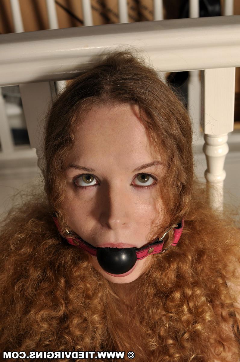 12P Fille célibataire aux cheveux roux bouclés arbore un bâillon-boule alors qu'elle est attachée à une balustrade