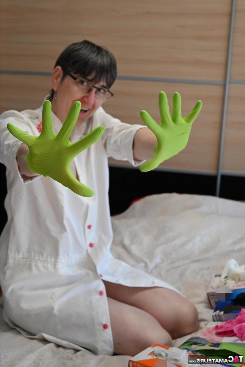 16P Amateurfrau kniet auf ihrem Bett und zieht Schichten von Latexhandschuhen an