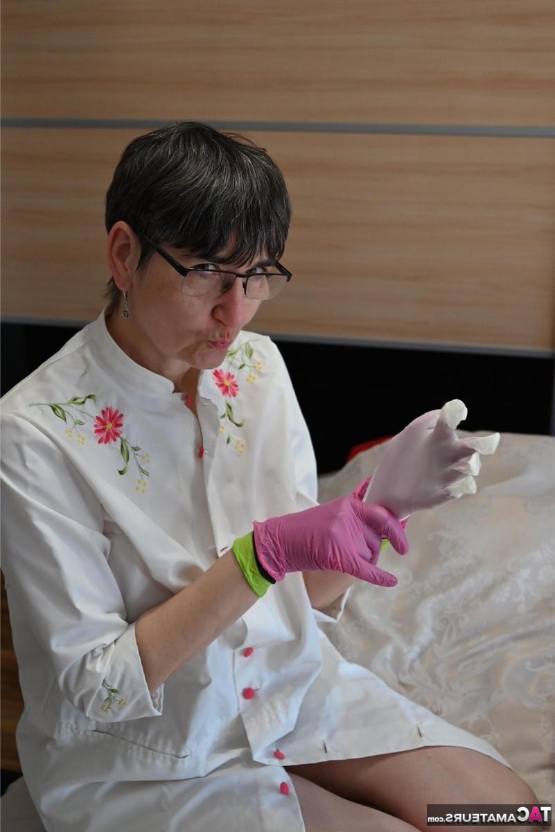 16P Amateurfrau kniet auf ihrem Bett und zieht Schichten von Latexhandschuhen an