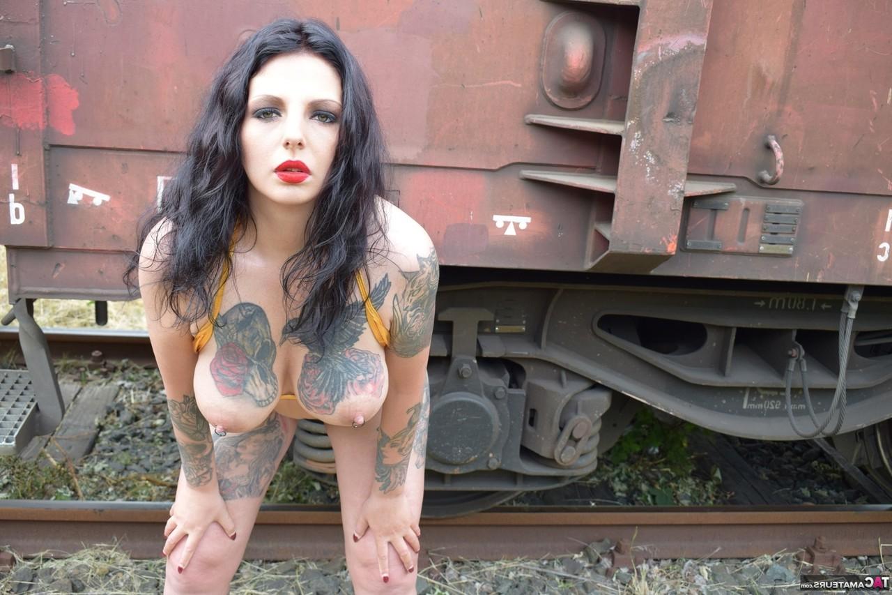 16P Tattooed brunette Lucy Ravenblood poses in the nude in front of railway cars