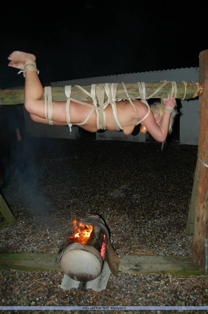 16P Rubia desnuda con una manzana en la boca es asada al fuego mientras está atada con una cuerda