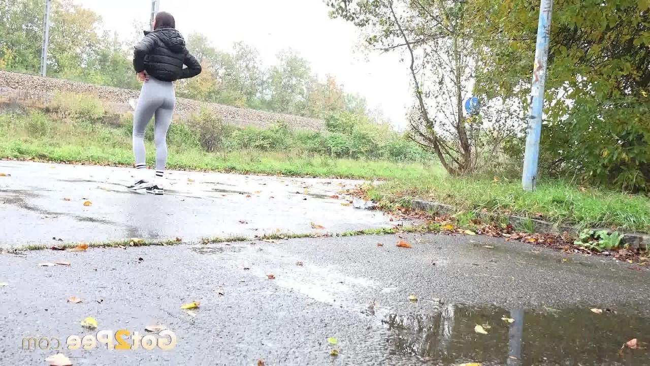 15P A garota caucasiana Maddi Black abaixa as leggings para fazer xixi na calçada molhada