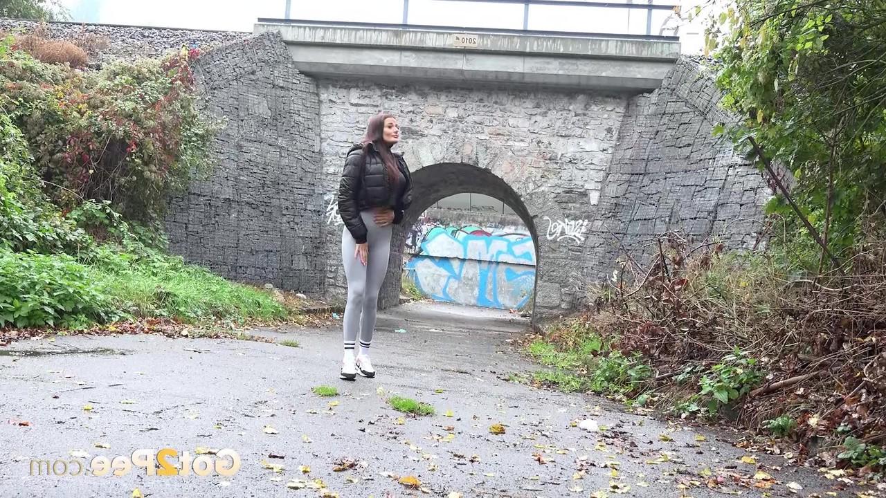 15P A garota caucasiana Maddi Black abaixa as leggings para fazer xixi na calçada molhada