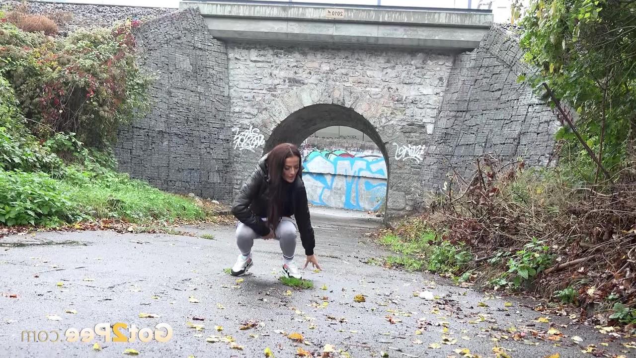 15P A garota caucasiana Maddi Black abaixa as leggings para fazer xixi na calçada molhada