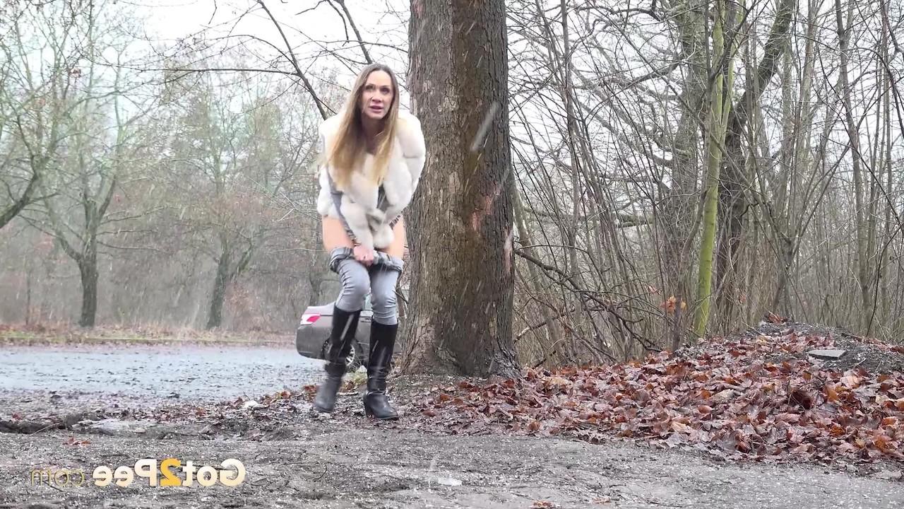 15P Das Solo-Girl Cynthia Vellons pisst an einem nassen Tag in eine Kiesauffahrt