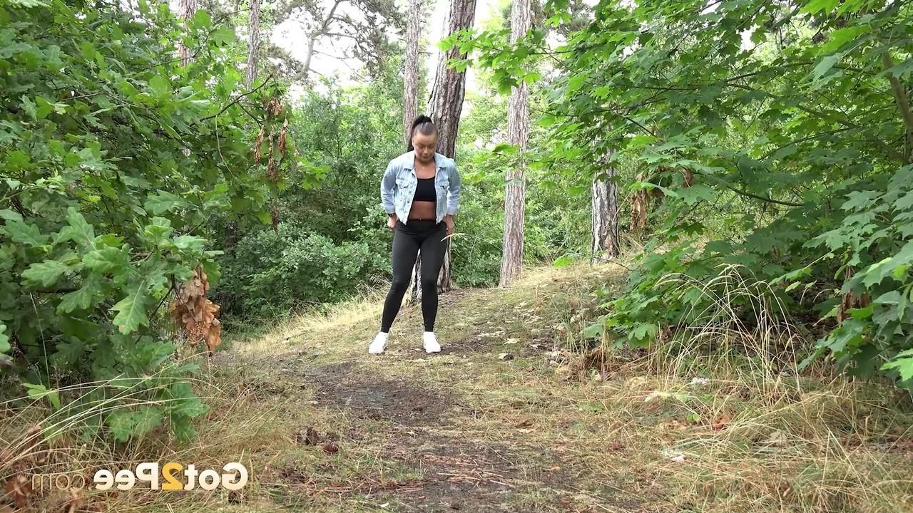 15P Das brünette Mädchen Dafne zieht ihre schwarzen Leggings herunter, um dringend im Wald zu pinkeln