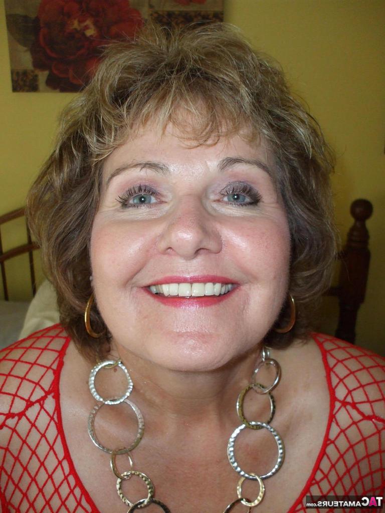 20P Mujer mayor se lame los labios mientras posa sola con un top de malla