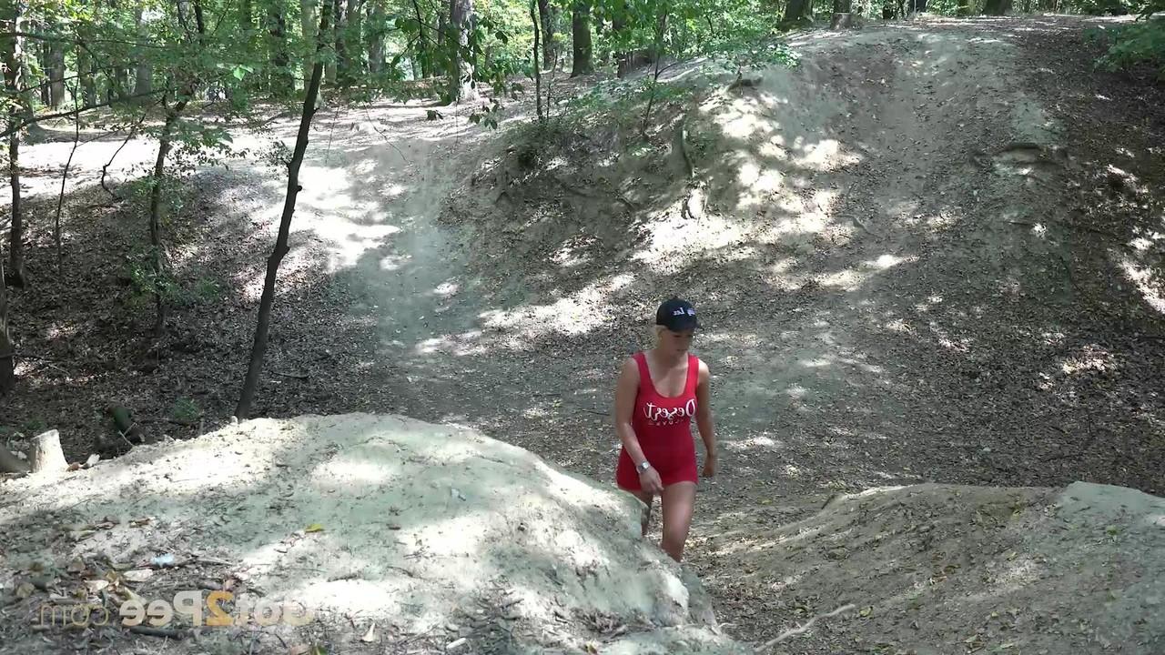 15P Das blonde Mädchen Licky Lex pinkelt im Wald über einen umgestürzten Baum