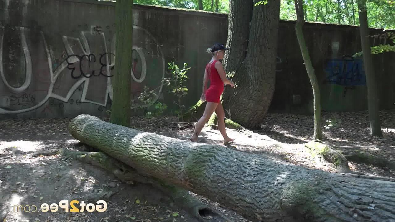15P Das blonde Mädchen Licky Lex pinkelt im Wald über einen umgestürzten Baum