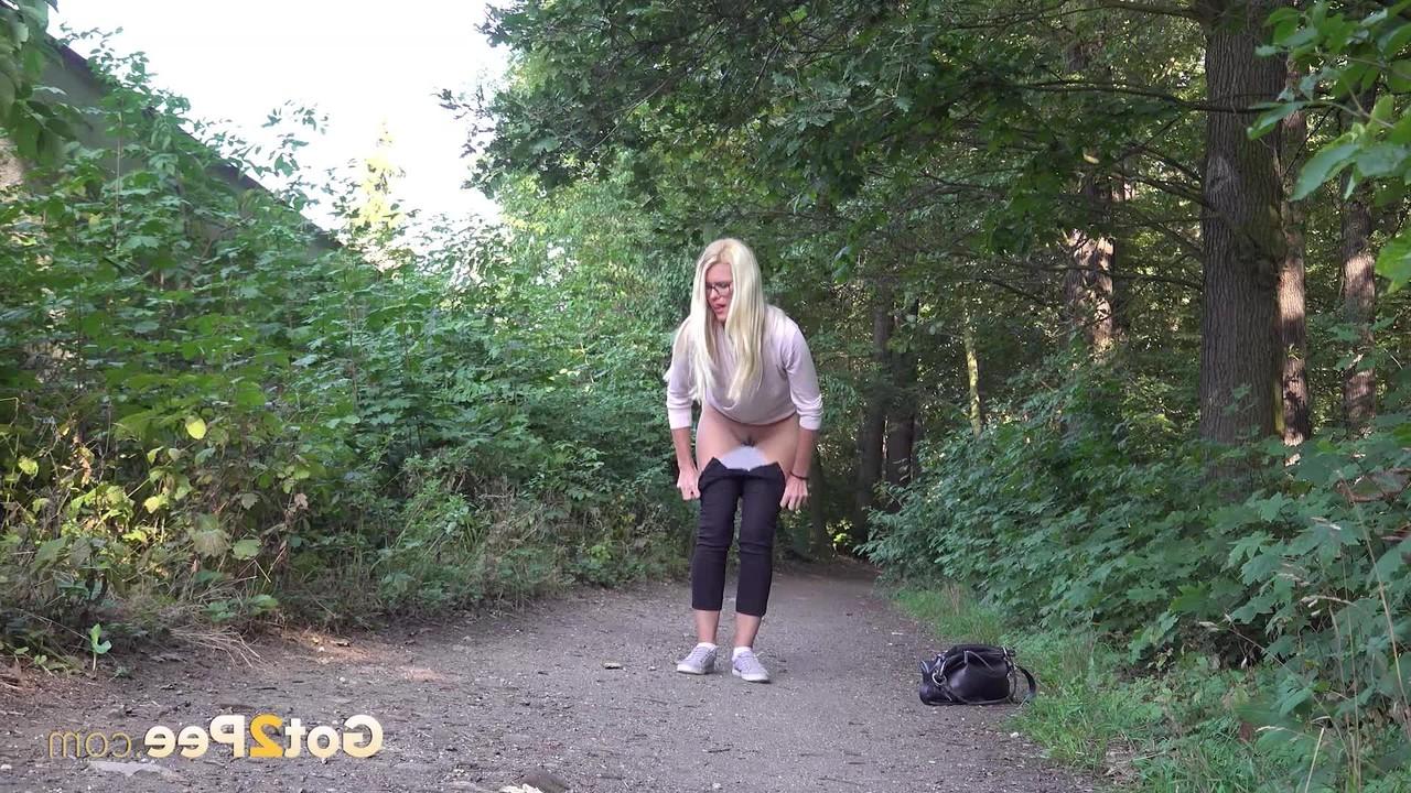 15P A loira Delphine faz xixi em um caminho de terra perto de alguma vegetação