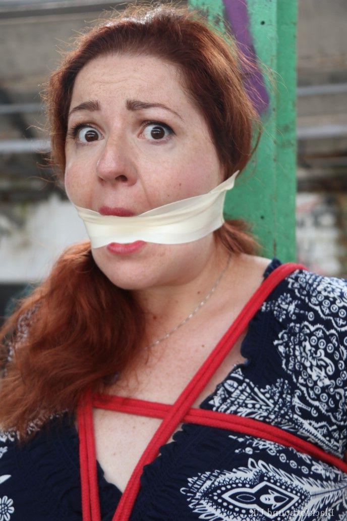 16P Redhead BBW finds herself gagged & tied to a post while clothed in a warehouse