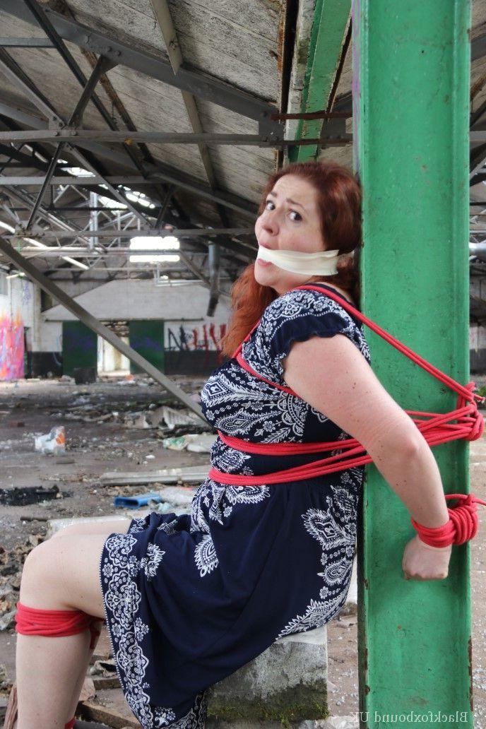 16P Redhead BBW finds herself gagged & tied to a post while clothed in a warehouse