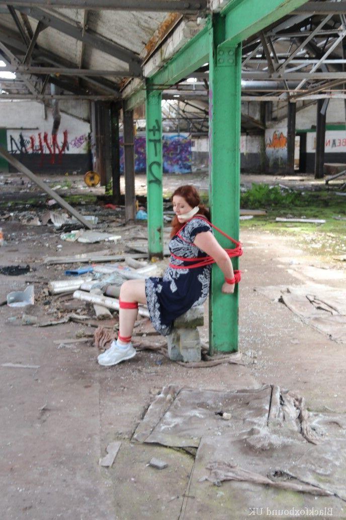 16P Redhead BBW finds herself gagged & tied to a post while clothed in a warehouse