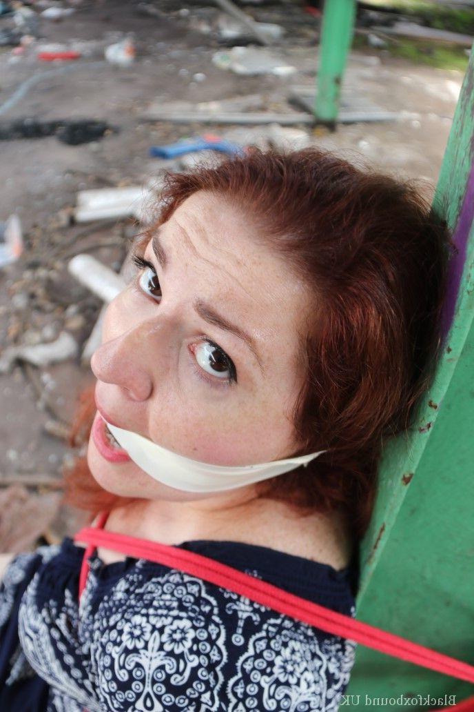 16P Redhead BBW finds herself gagged & tied to a post while clothed in a warehouse