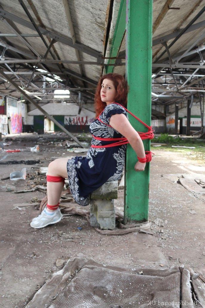 16P Redhead BBW finds herself gagged & tied to a post while clothed in a warehouse