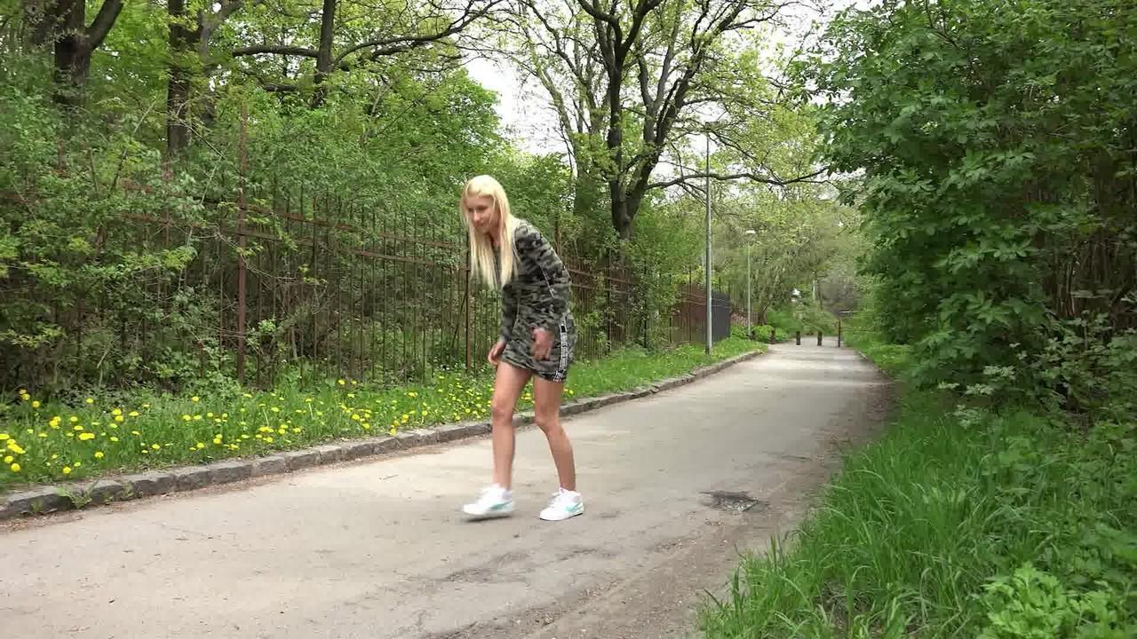 15P Nykla, une fille blanche aux cheveux blonds, pisse sur une route pavée.