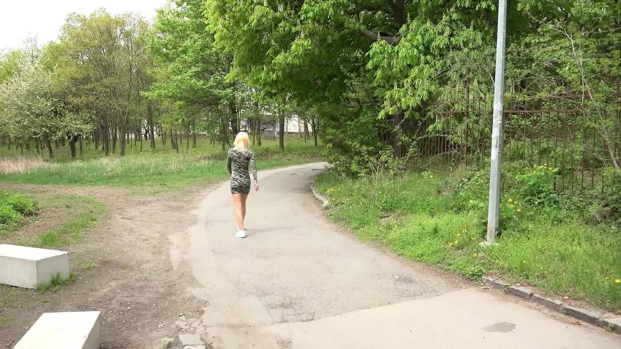 15P Nykla, une fille blanche aux cheveux blonds, pisse sur une route pavée.