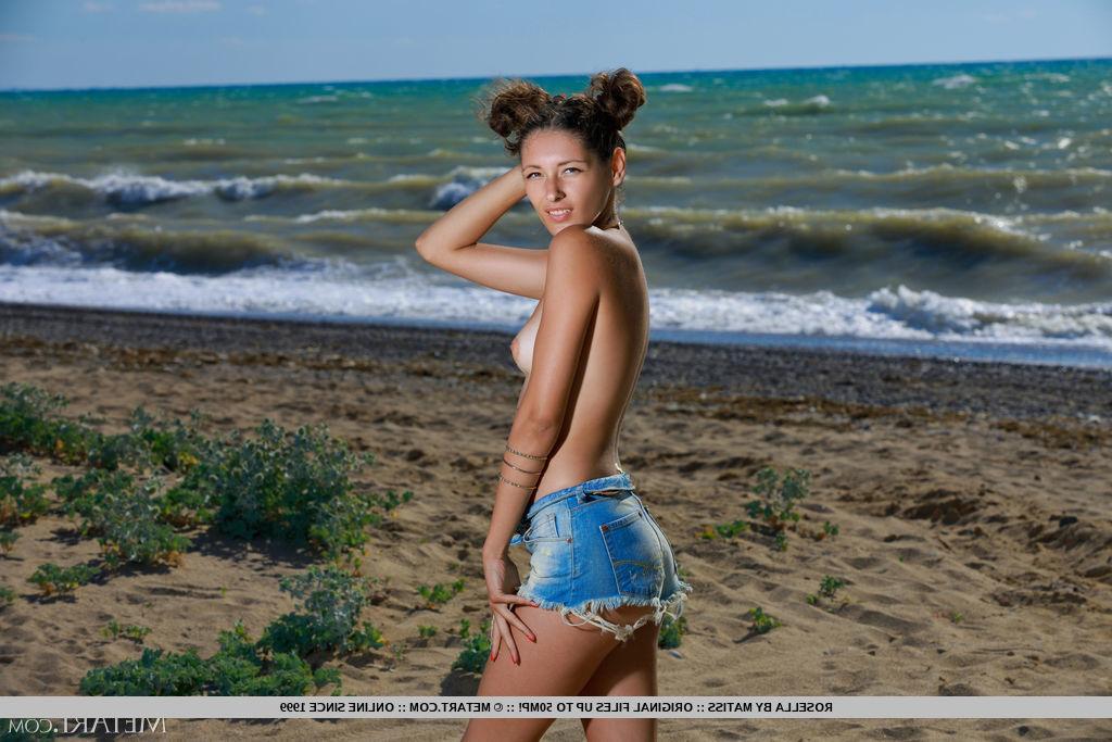 18P La joven caliente Rosella lleva el pelo recogido mientras está totalmente desnuda en la playa