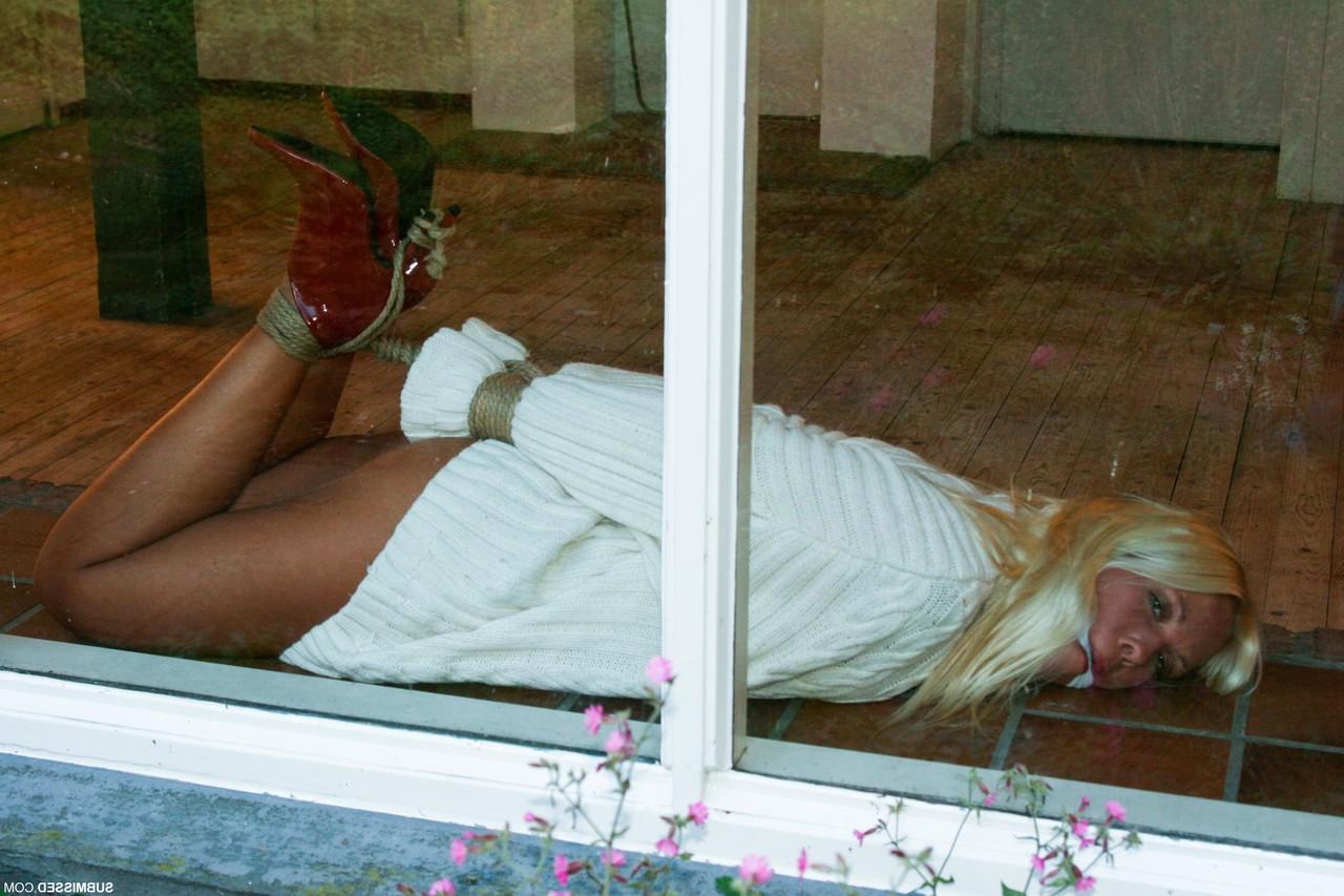 17P Hogtied and cleave gagged blonde in red high heels Natalie lays by the window