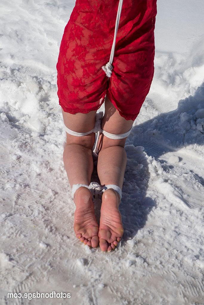 16P Une femelle blanche est tenue debout et obligée de se tenir debout et de s'agenouiller dans la neige.