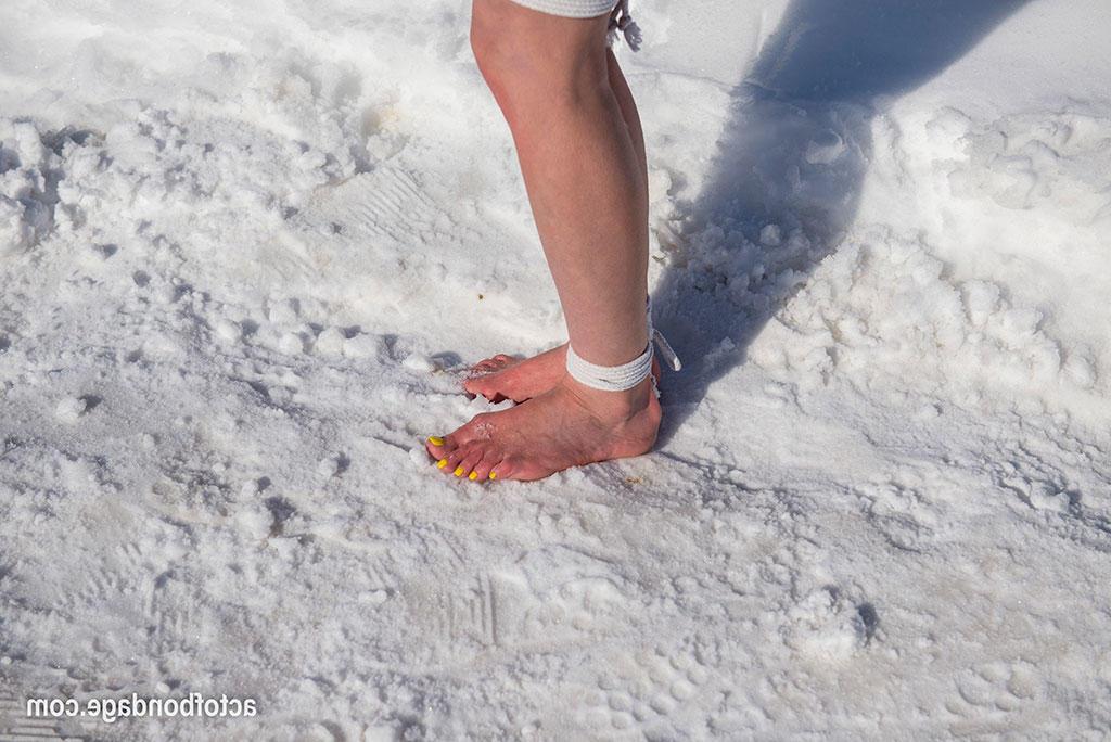 16P Une femelle blanche est tenue debout et obligée de se tenir debout et de s'agenouiller dans la neige.