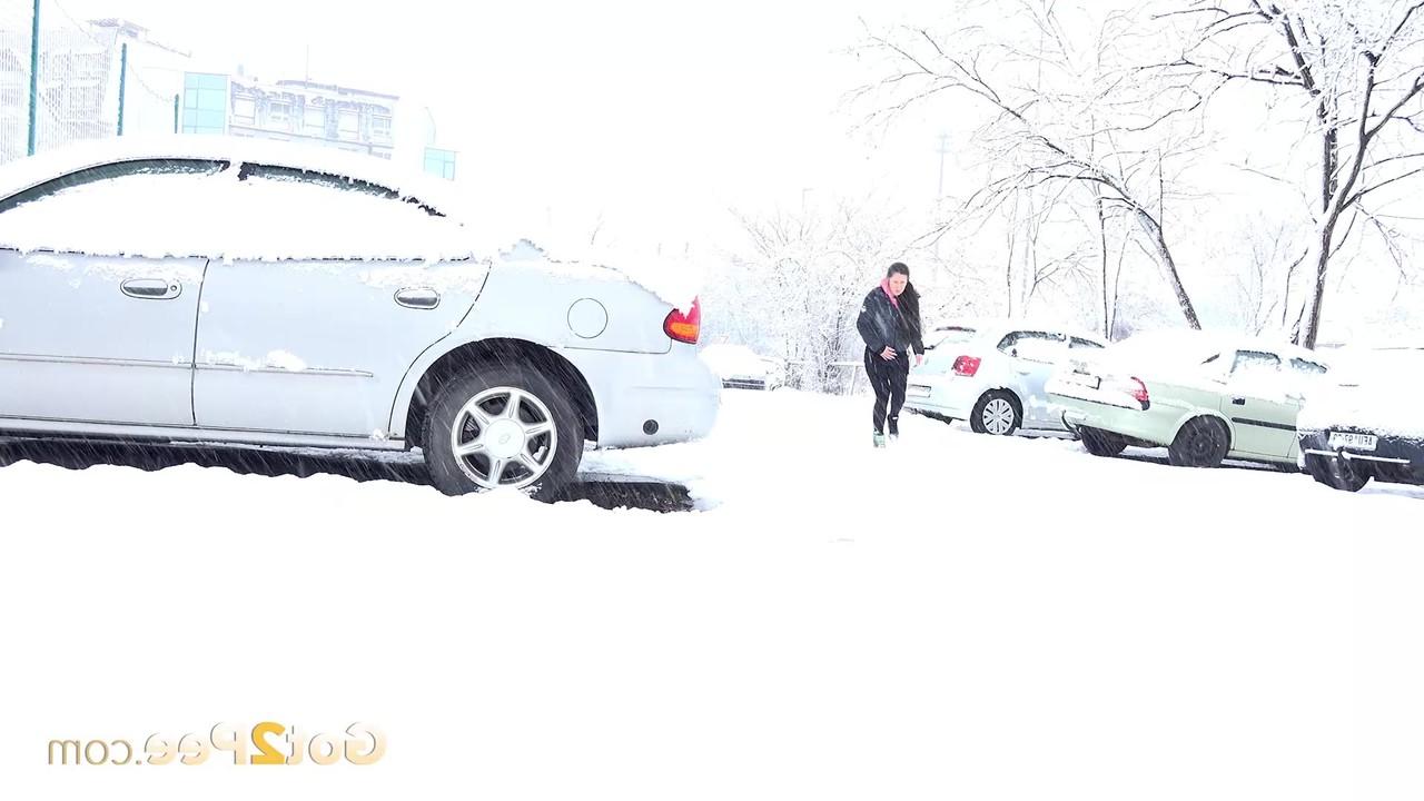 15P Lara Fox mija ao lado de um veículo estacionado durante uma tempestade de neve