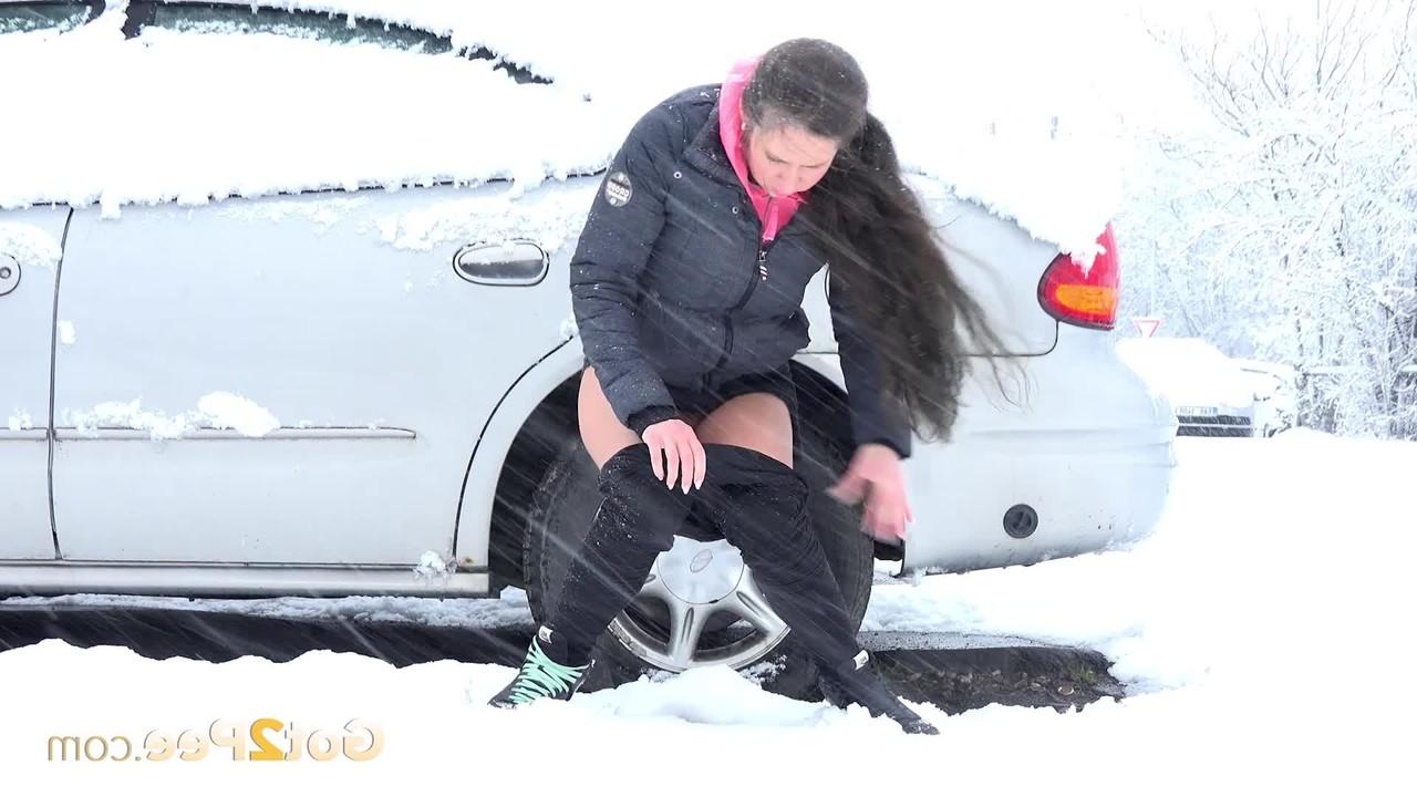 15P Lara Fox mija ao lado de um veículo estacionado durante uma tempestade de neve