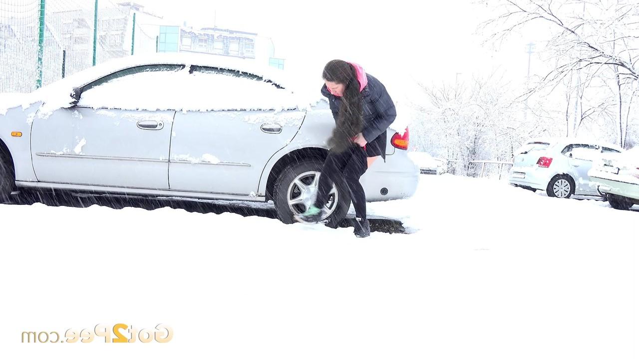 15P Lara Fox mija ao lado de um veículo estacionado durante uma tempestade de neve