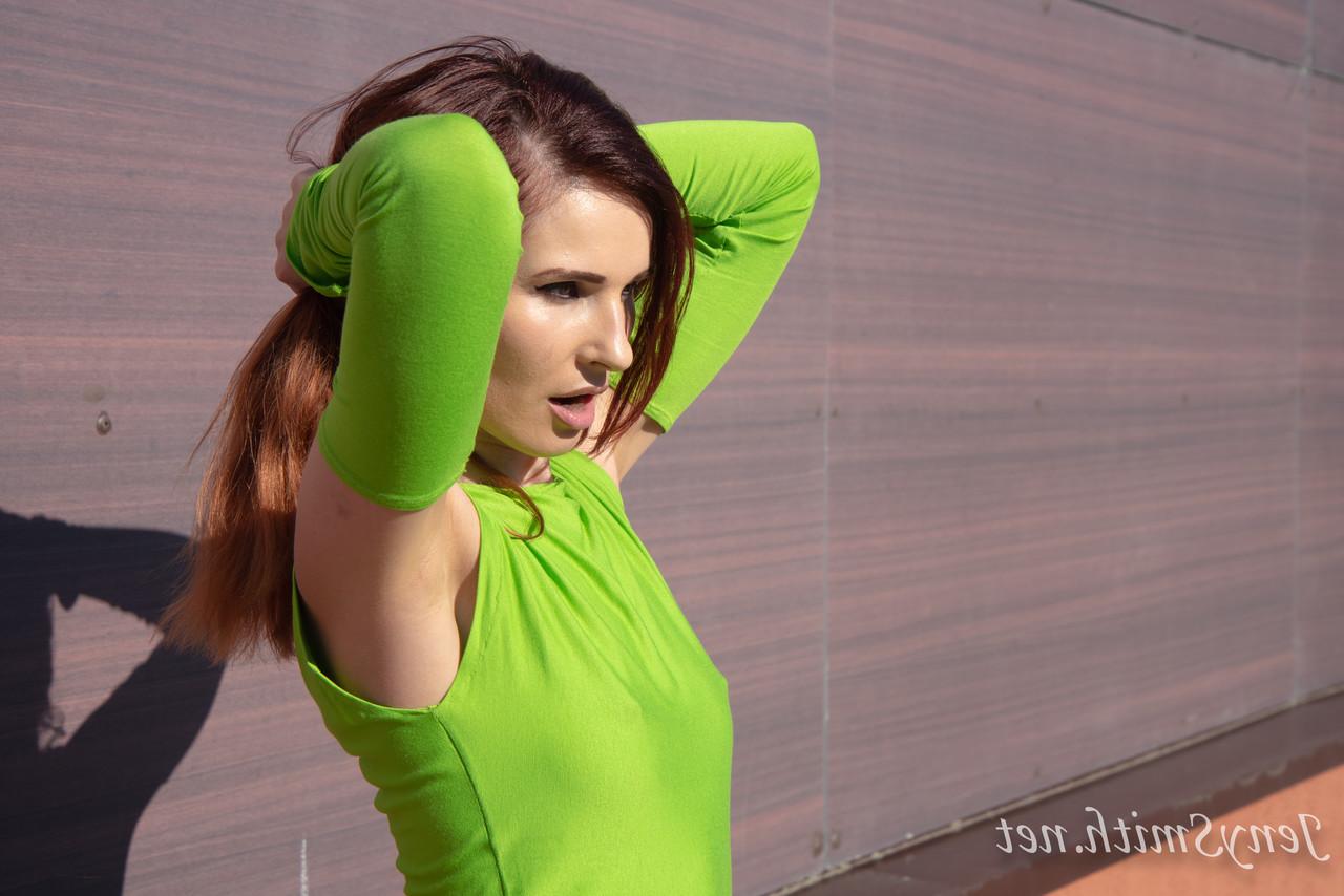 15P Jeny Smith, une fille mince vêtue d'une robe verte, montre ses fesses et pose en plein air.