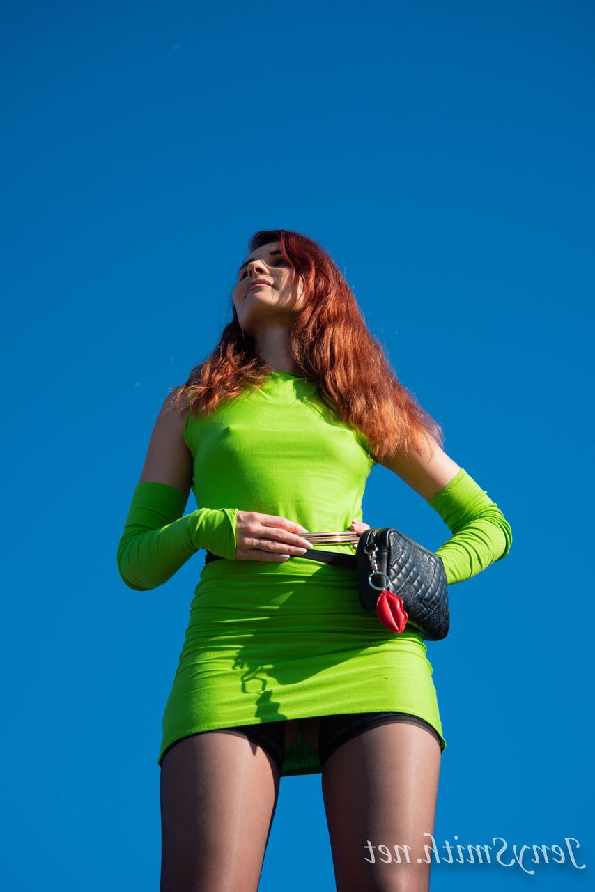 15P Jeny Smith, une fille mince vêtue d'une robe verte, montre ses fesses et pose en plein air.