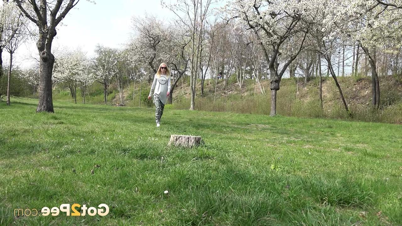 15P A loira Debora senta em um toco em um parque enquanto mija