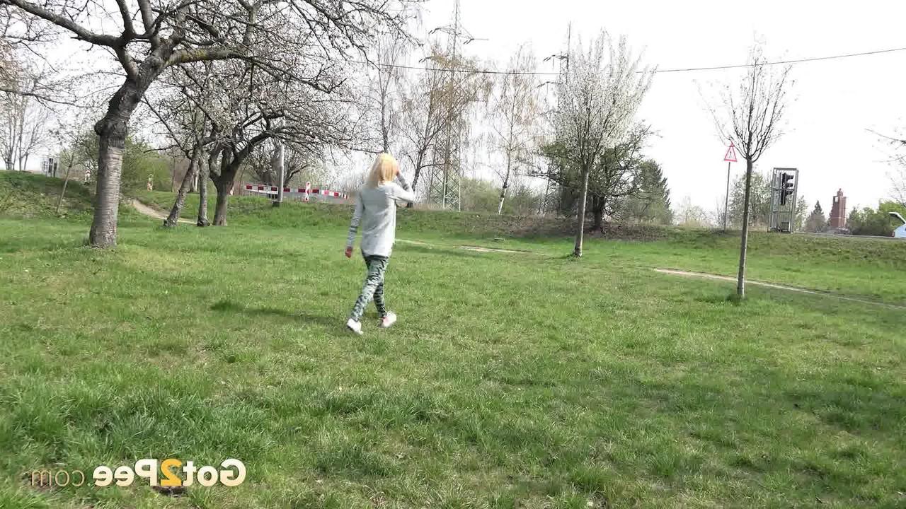 15P A loira Debora senta em um toco em um parque enquanto mija