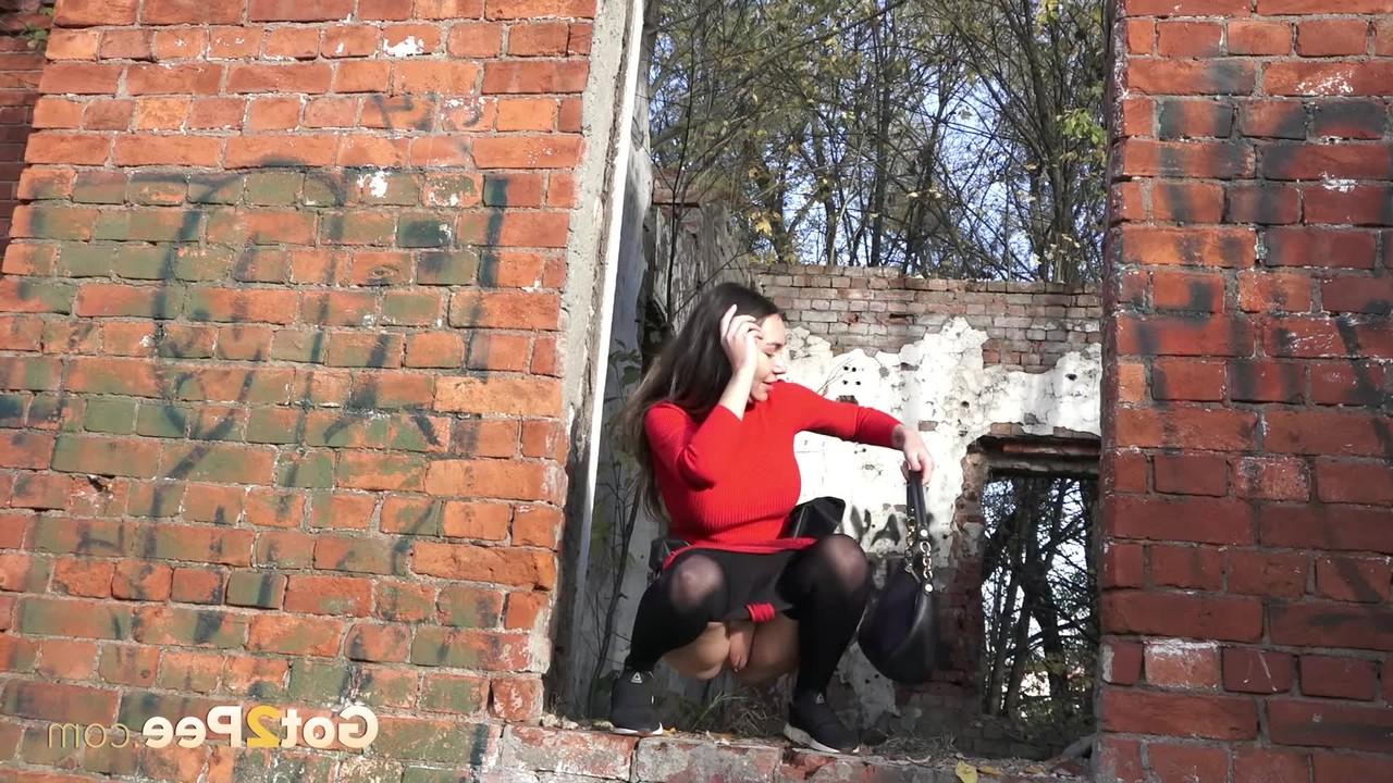 15P Pretty girl Sasha squats for a pee by a brick building in pantyhose