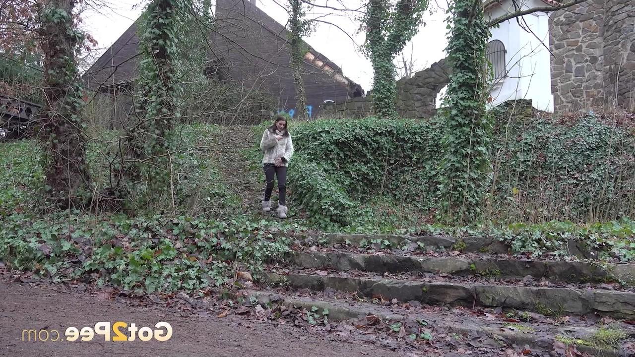 15P A garota branca Victoria Daniels faz xixi ao lado de um caminho com botas de inverno e um casaco