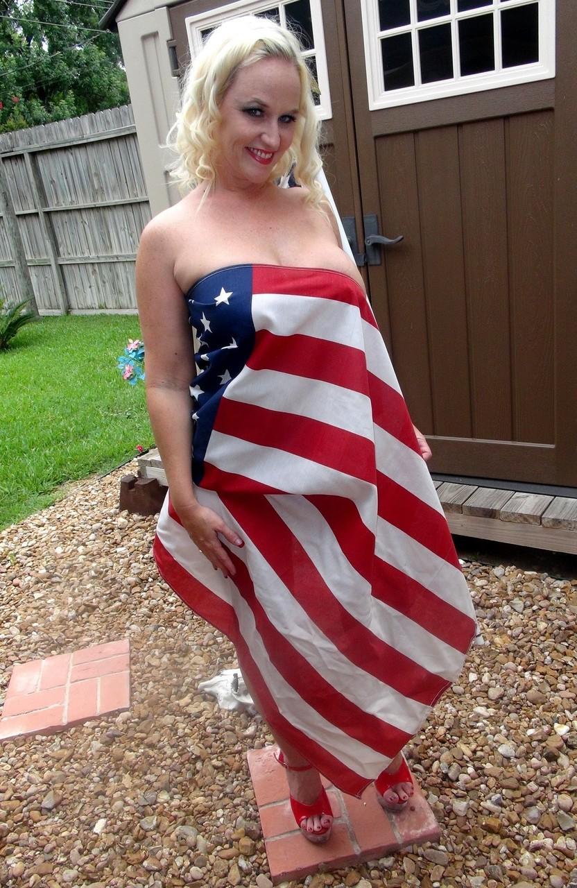 17P A amadora loira Dee Siren segura uma bandeira americana enquanto faz topless com uma tanga vermelha