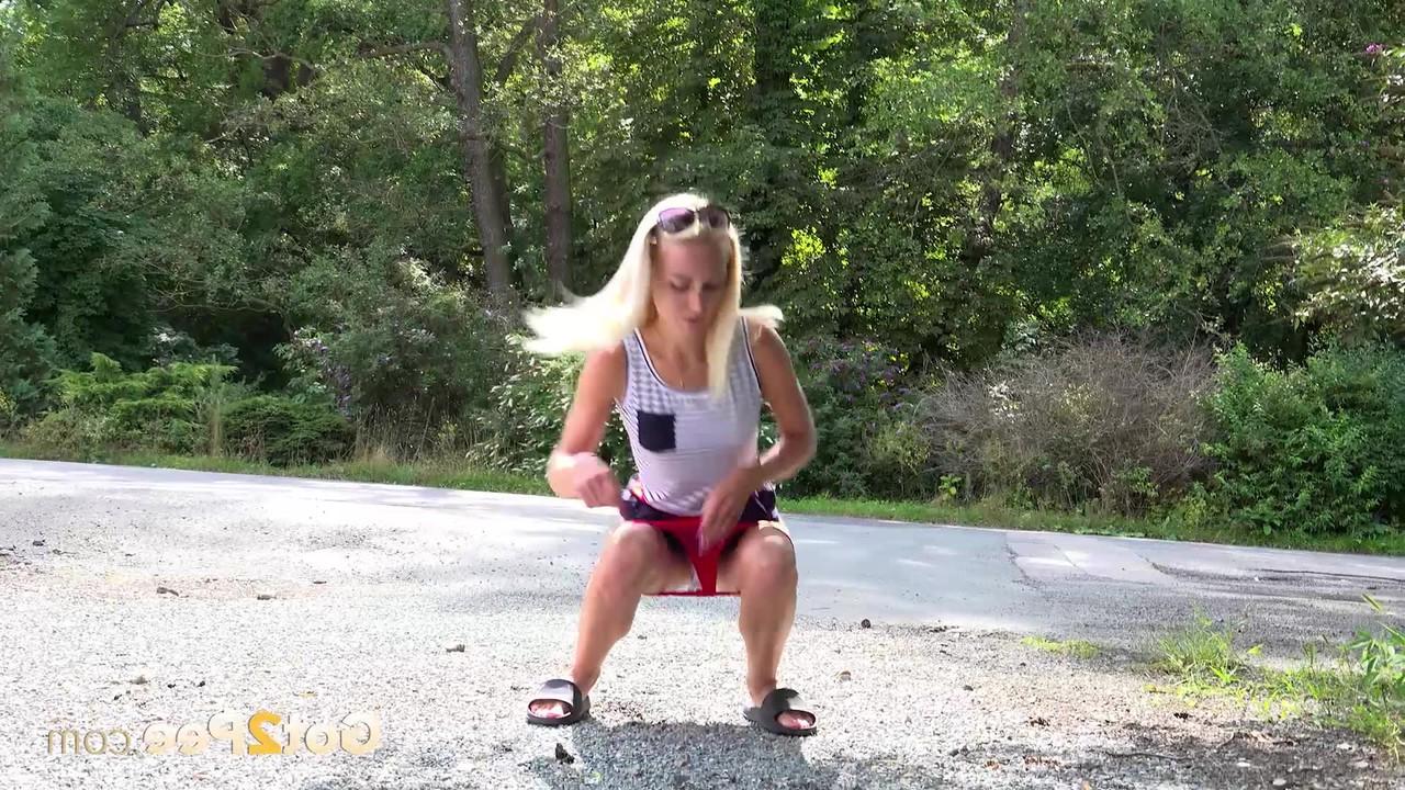 15P La petite blonde Debora s'accroupit pour pisser sur le bord d'une route pendant que les voitures passent.