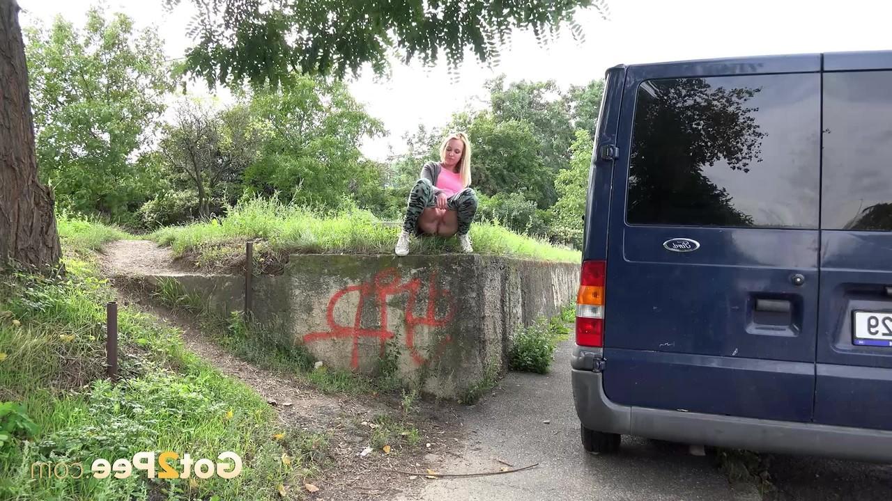 15P La blonde Debora pisse sur le côté d'un mur de soutènement près d'un trottoir.