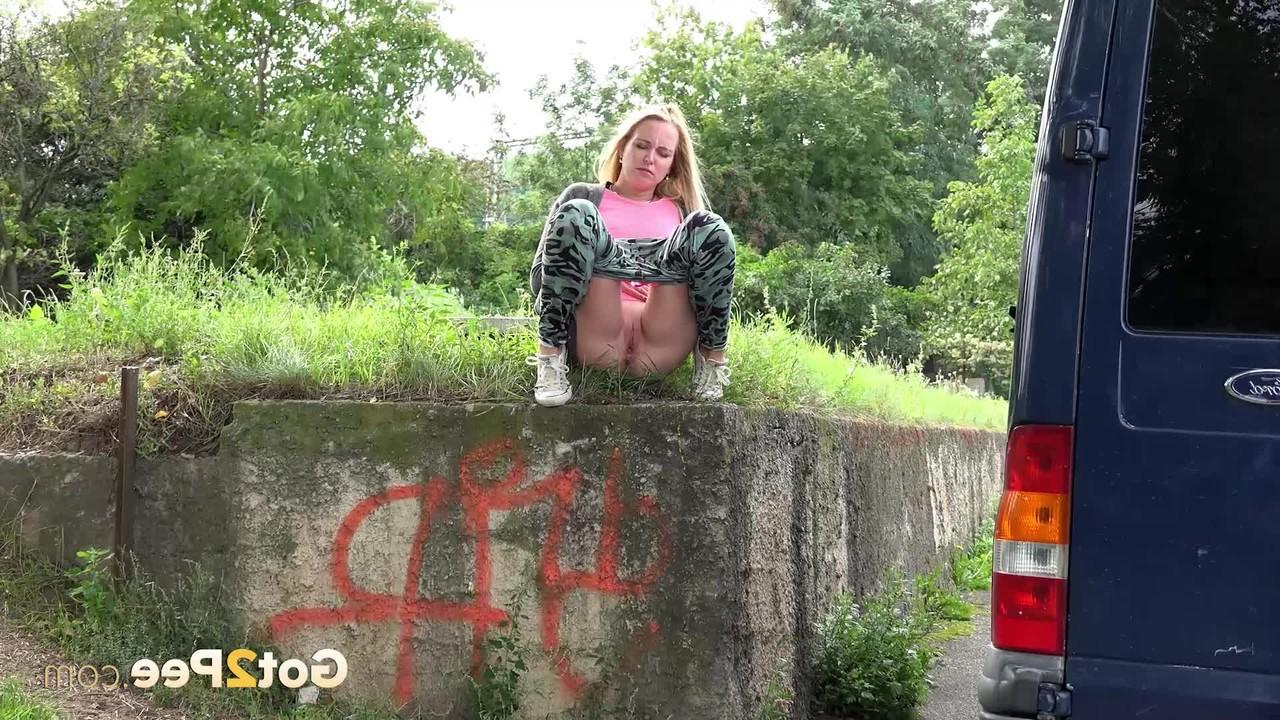 15P La blonde Debora pisse sur le côté d'un mur de soutènement près d'un trottoir.