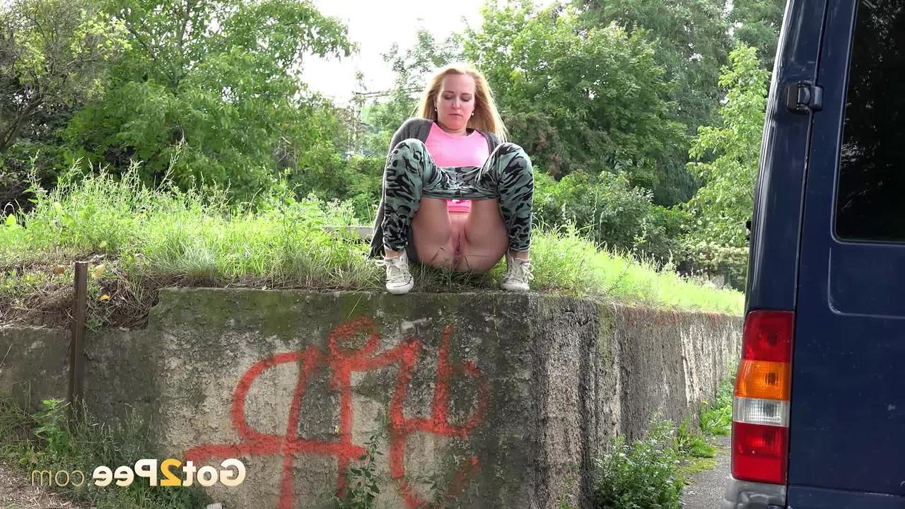 15P La blonde Debora pisse sur le côté d'un mur de soutènement près d'un trottoir.