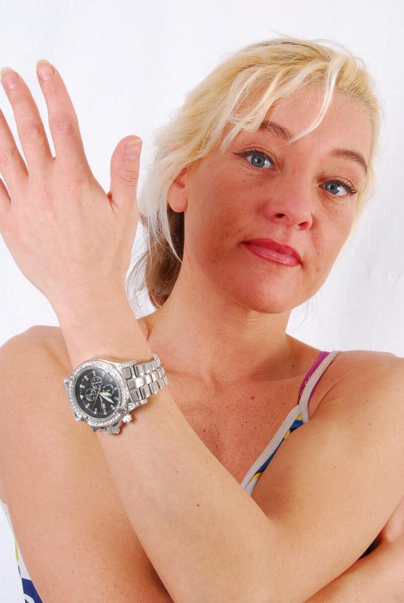 16P Lilly, la rubia de ojos azules, modela un enorme reloj de metal durante una acción segura para el trabajo