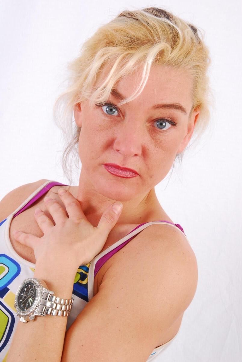 16P Lilly, la rubia de ojos azules, modela un enorme reloj de metal durante una acción segura para el trabajo
