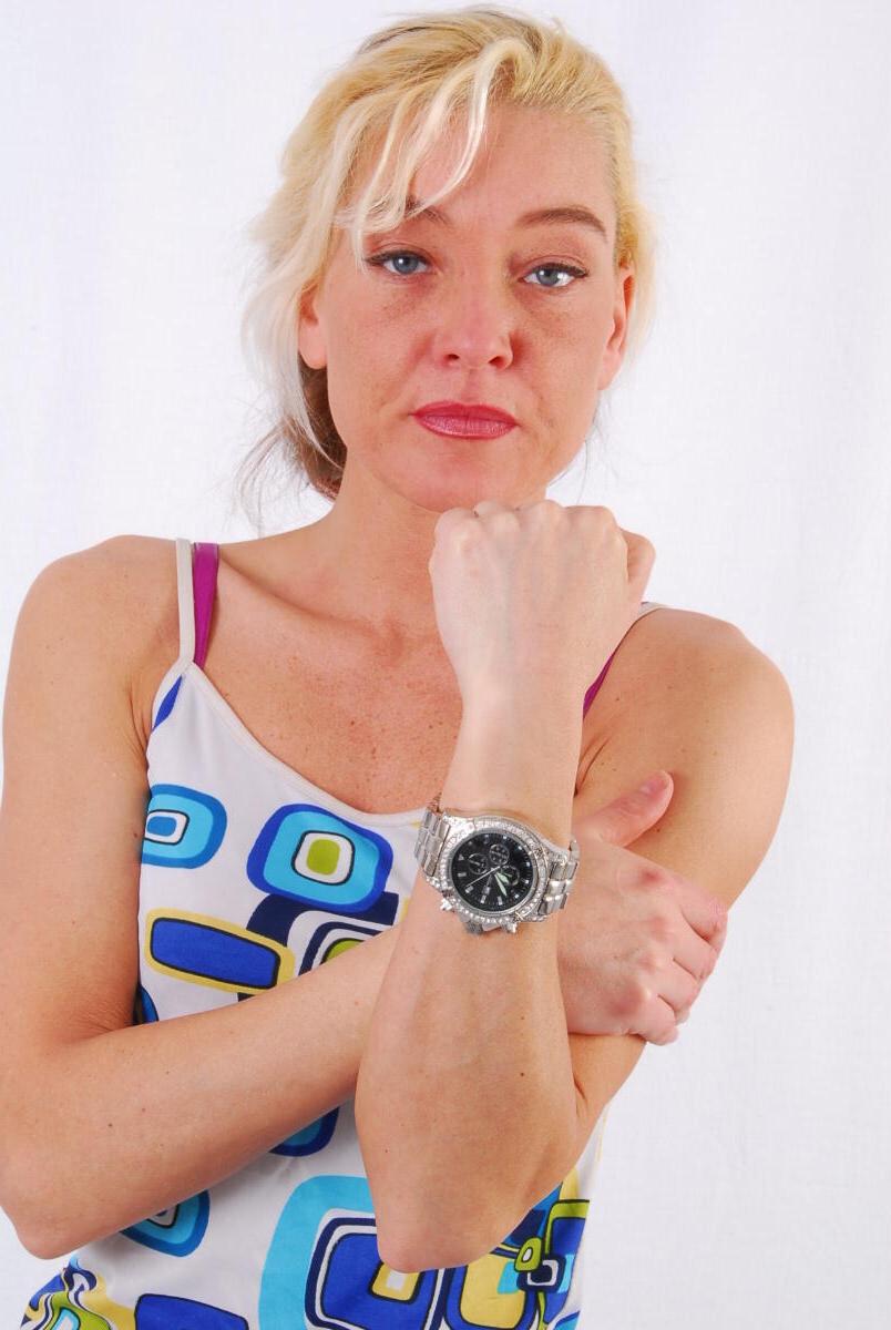16P Lilly, la rubia de ojos azules, modela un enorme reloj de metal durante una acción segura para el trabajo